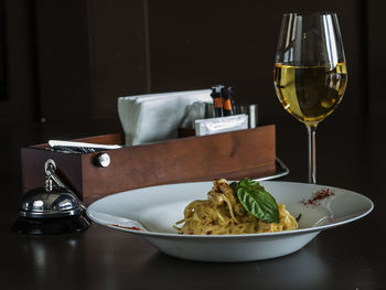 Close-up of spaghetti with cream sauce served in plate by drink on table