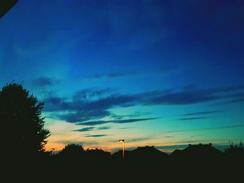 Low angle view of silhouette trees against blue sky