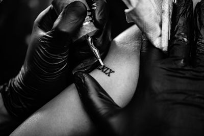 Cropped image of man tattooing on woman hand