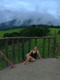 Portrait of young woman on railing against sky