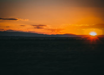 Scenic view of silhouette landscape against orange sky