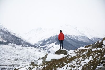 Rear view of person on snowcapped mountain against sky