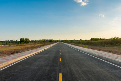 Empty road by landscape against sky