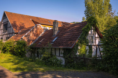 Old house amidst trees and plants against sky