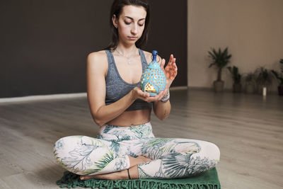 Young woman meditates alone in yoga studio with aroma lamp