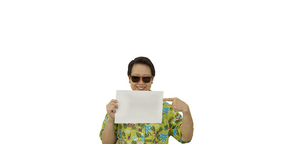 Portrait of man holding sunglasses against white background