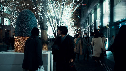 Rear view of people walking on illuminated building