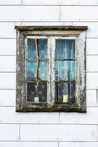 Broken windows of an old, abandoned house with asbestos wall tiles
