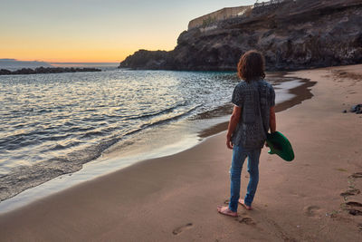 Rear view of woman on beach during sunset