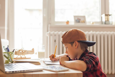 Cool elementary student doing his homework in the living room.