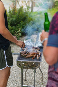 Midsection of man preparing food on barbecue grill