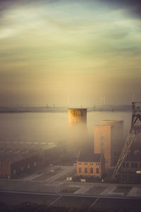 High angle view of city by sea against sky during sunset
