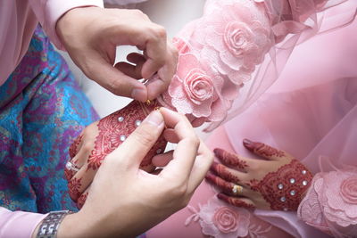 Midsection of bridegroom putting bracelet on bride during wedding ceremony