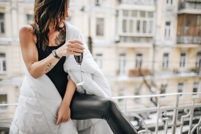 Woman having red wine while wrapped in blanket at balcony