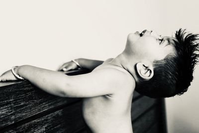 Boy looking up while standing by holding headboard of bed at home