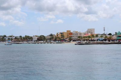 Scenic view of sea by buildings against sky