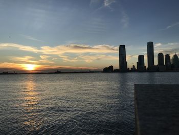 Scenic view of sea by buildings against sky during sunset