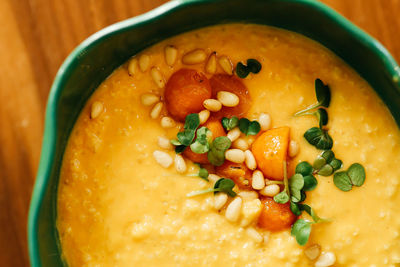 Yellow millet vegetarian healthy food porridge decorated with herbs and pumpkin on a plate in a cafe