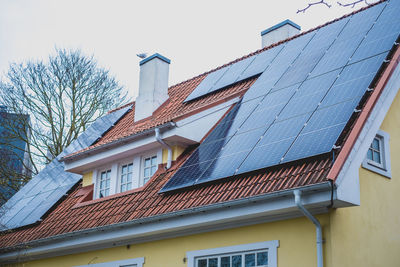 Close-up of solar panels installed on historic building gable roof with chimney.