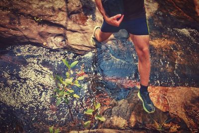 Low section of man crossing a stream