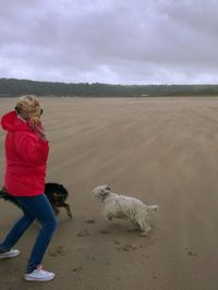 Full length of woman standing on beach against cloudy sky