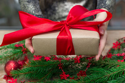 Midsection of woman holding christmas present at table