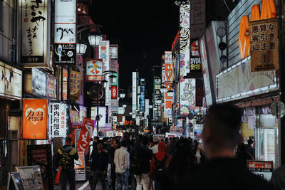 People on illuminated street in city at night