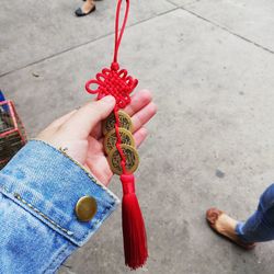 Cropped hand of woman holding decoration on footpath in city