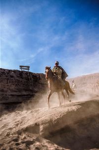Man riding motorcycle on desert against sky