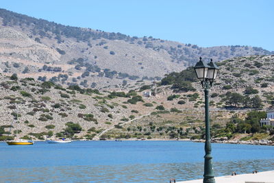 Scenic view of river by mountains against clear blue sky