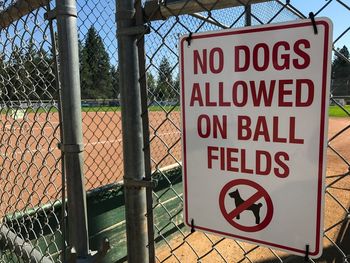 Close-up of warning sign on chainlink fence