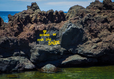 Rock formation by sea against mountain