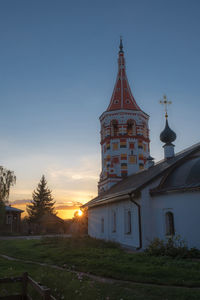 Tower amidst buildings against sky during sunset