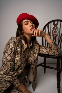 Portrait of young woman with chair against gray background