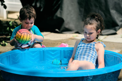 Siblings playing near a water basin in the back yard