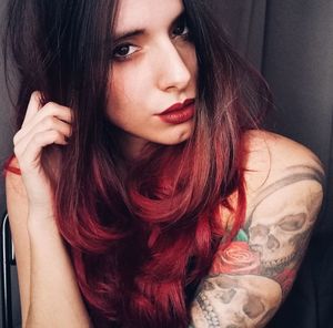 Close-up portrait of beautiful young woman sitting against wall