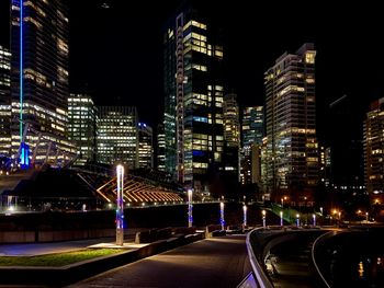 Illuminated modern buildings in city against sky at night