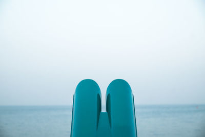 Low section of person on blue sea against clear sky