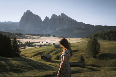 Side view of woman standing on mountain against sky