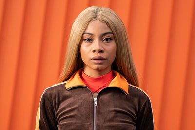 Young african american woman with long blonde hair and sportswear on an orange background