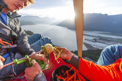 Two men using an apple peeler sitting on portaledge at sunset