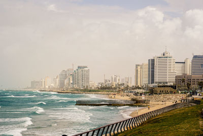 Sea and buildings in city against sky