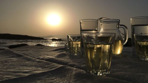 Close-up of beer in sea against sky during sunset