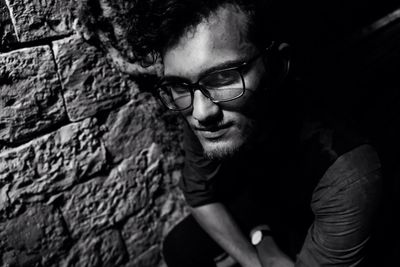 Portrait of young man wearing eyeglasses against wall