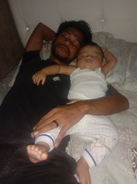 High angle view of father with baby on bed