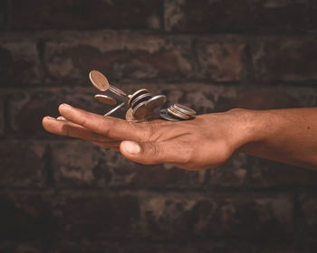 Close-up of man holding hands against wall