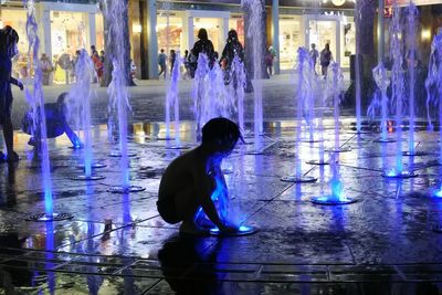 Silhouette people in illuminated water at night
