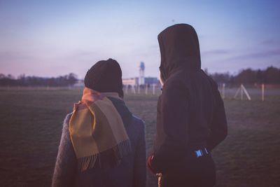 Rear view of couple standing on field against sky