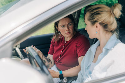 Portrait of friends using mobile phone while sitting in car