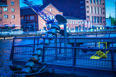 Man with umbrella on river against illuminated buildings in city